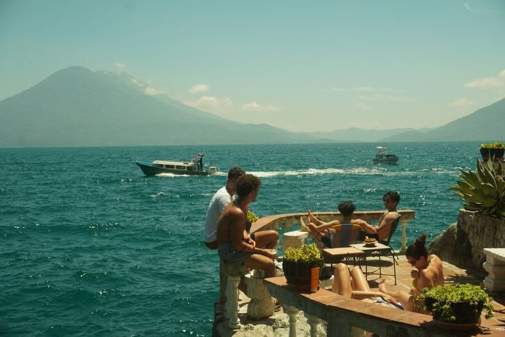 Friends on a lakeside terrace with a volcano across the water